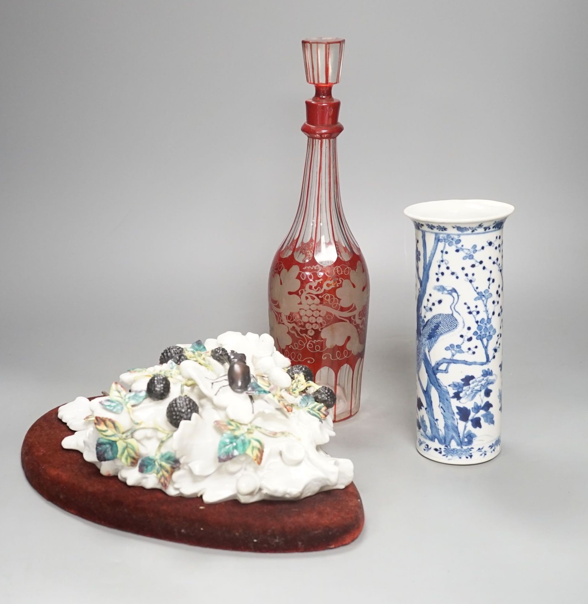 An etched ruby glass decanter, a Chinese blue and white sleeve vase and a continental ceramic basket wall pocket- decanter 34cms high.